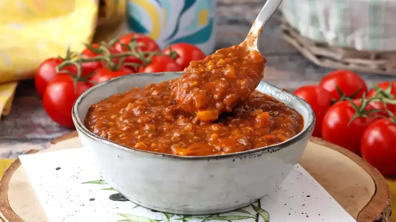 En skål med mustig bolognese, perfekt för ett gott bolognese recept. Färska tomater i bakgrunden.