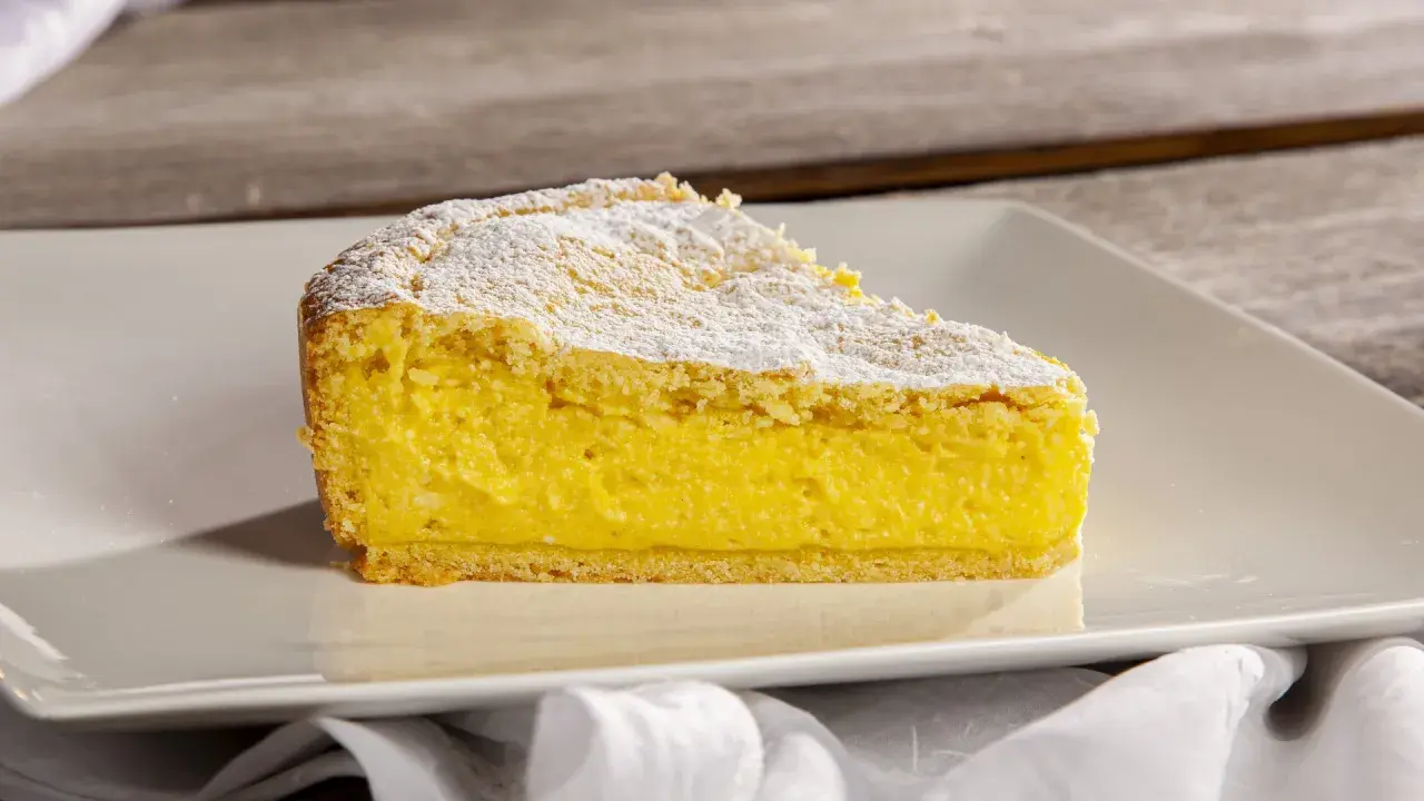 Una fetta di crostata di ricotta, con la sua base dorata e il ripieno cremoso, spolverata di zucchero a velo.