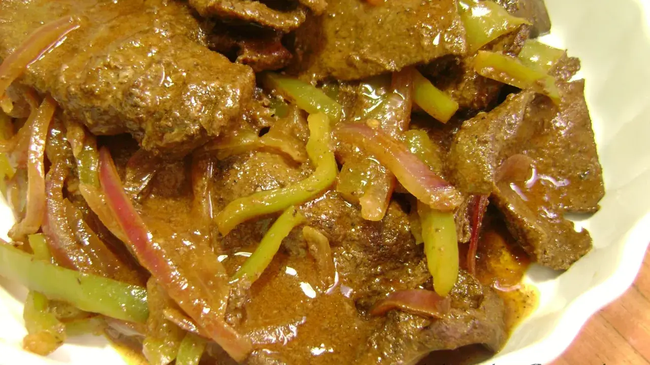 Sabroso hígado encebollado con pimientos verdes y cebolla morada en una salsa rica. Un plato casero reconfortante.