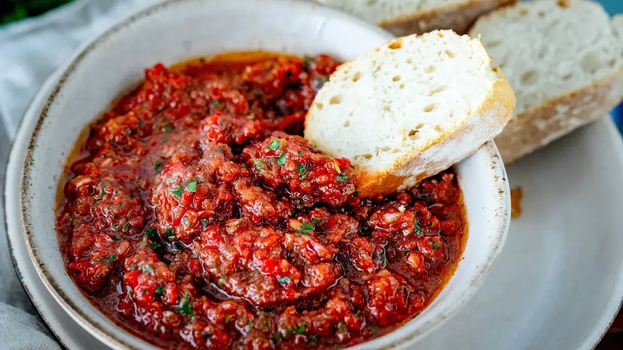 Schüssel mit würzigem Acili Ezme, einem scharfen türkischen Dip aus Tomaten und Paprika, serviert mit frischem Brot.