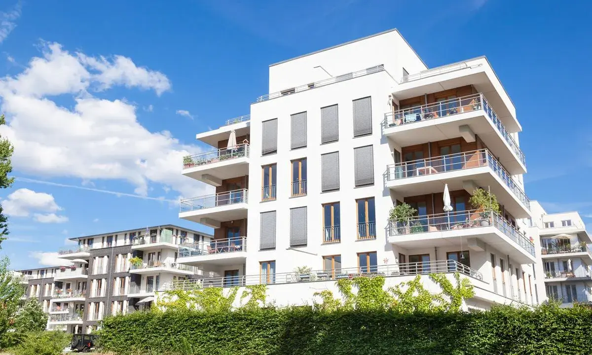 Immeubles modernes avec balcons fleuris, sous un ciel bleu. Un projet immobilier qui pourrait bénéficier de la loi Borloo pour son accessibilité.