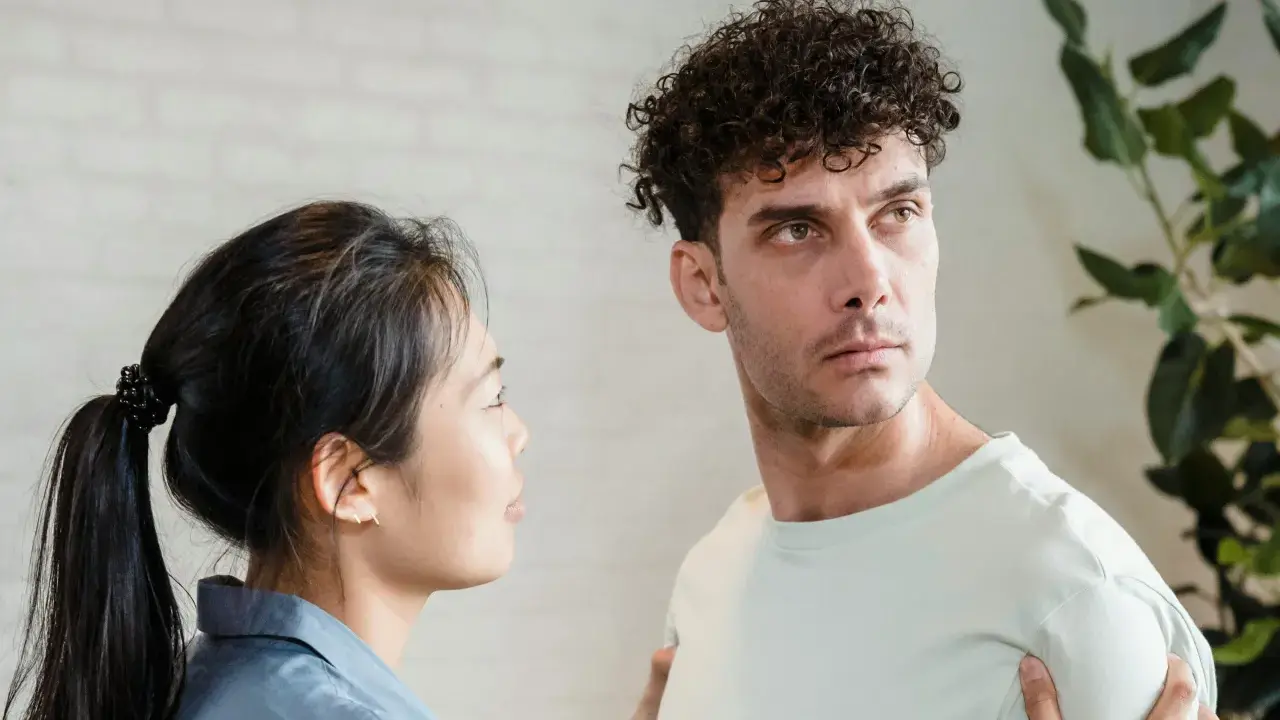 Un homme au regard intense, peut-être un pervers narci, semble ignorer une femme qui le regarde avec inquiétude.