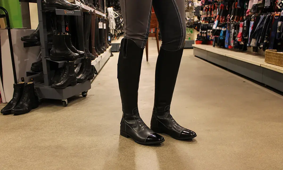 Schwarze, glänzende Reitstiefel angezogen, bereit für den Stall.