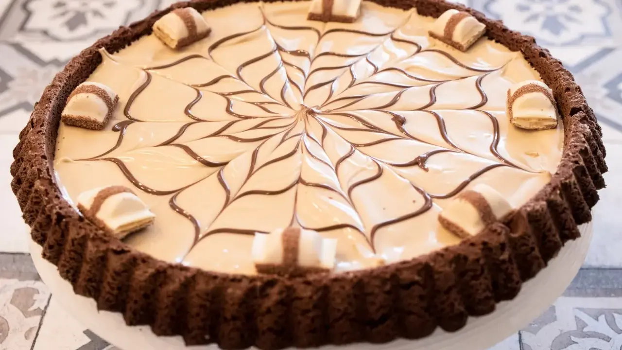 Torta Kinder Bueno con decorazione a ragnatela di cioccolato e pezzi di Kinder Bueno.
