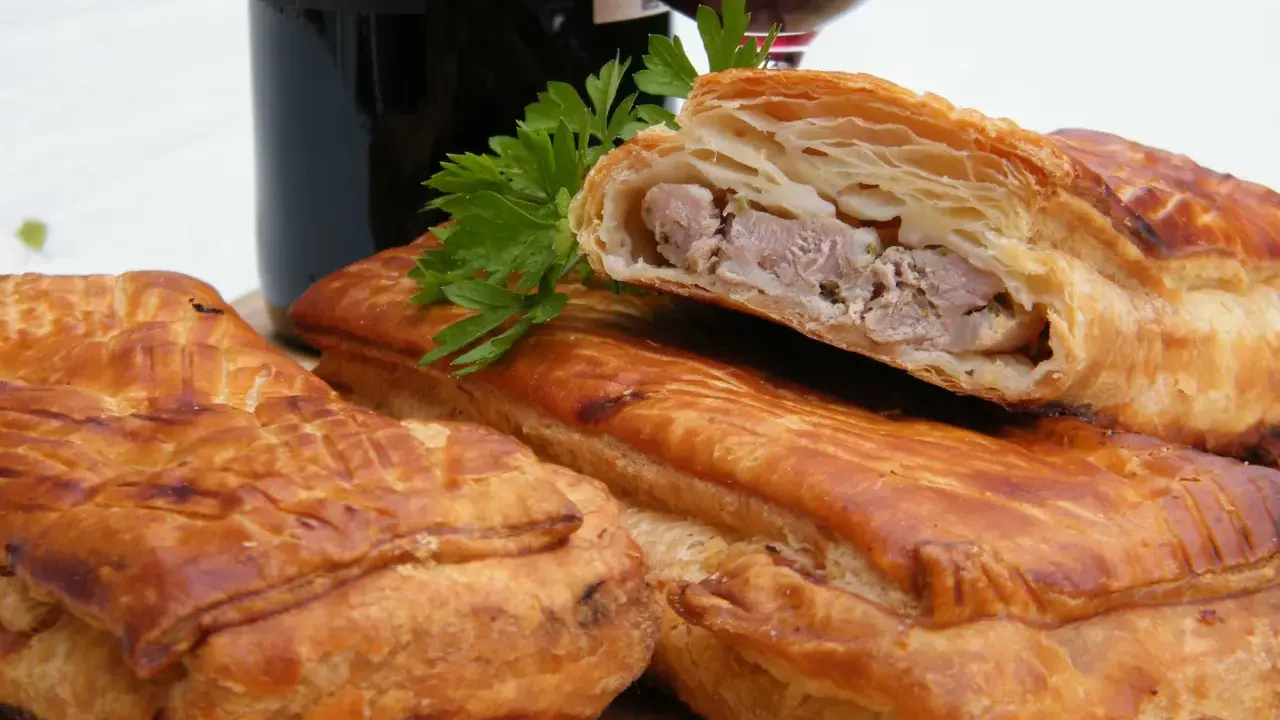 Pâté en croûte, une spécialité lorraine savoureuse, garni de viande et d'herbes, prêt à être dégusté avec un verre de vin.