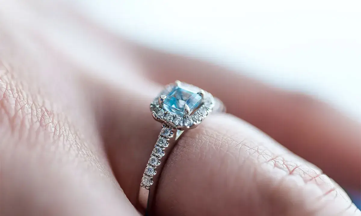 Un anello di fidanzamento con un acquamarina centrale e diamanti, simbolo di un amore eterno e profondo.