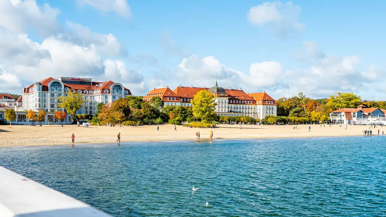 Piękna plaża z hotelami i spacerującymi ludźmi, idealne miejsce na weekendowy relaks nad morzem.