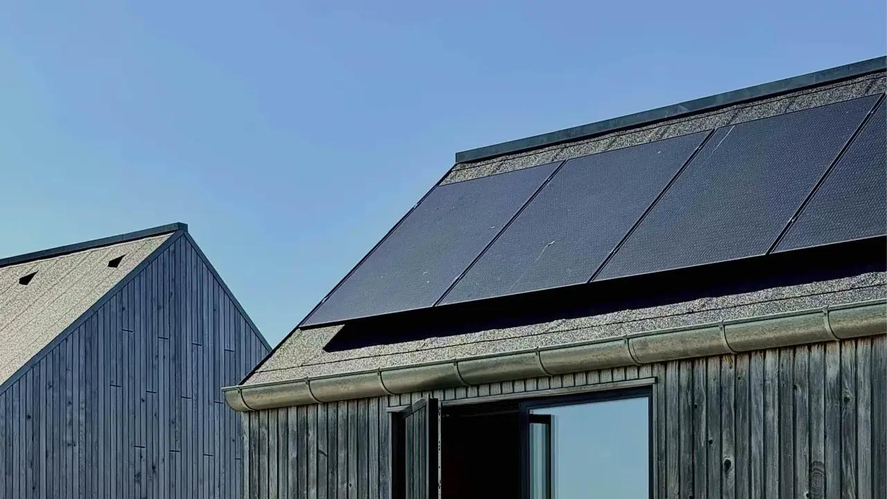 Mörka träfasader möter tak med solpaneler. En modern, hållbar design som fångar solens energi, nästan som en denim solar-dröm.