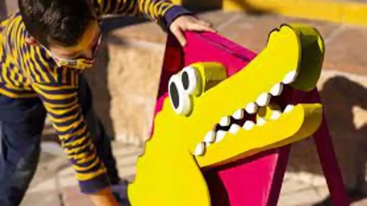 Un niño interactúa con un cocodrilo amarillo de utilería, parte de un espectáculo de teatro infantil en Málaga.