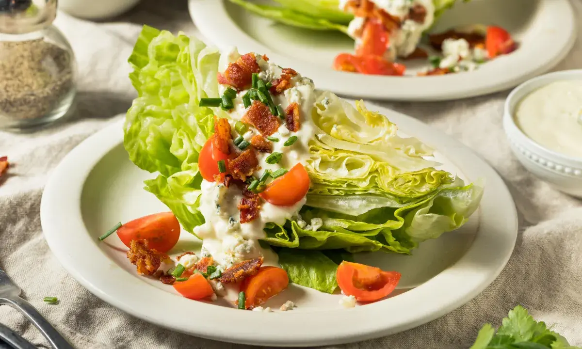Eisbergsalat-Rezept: knackige Salatspalten mit cremiger Blauschimmelkäse-Dressing, Speck und Tomaten.