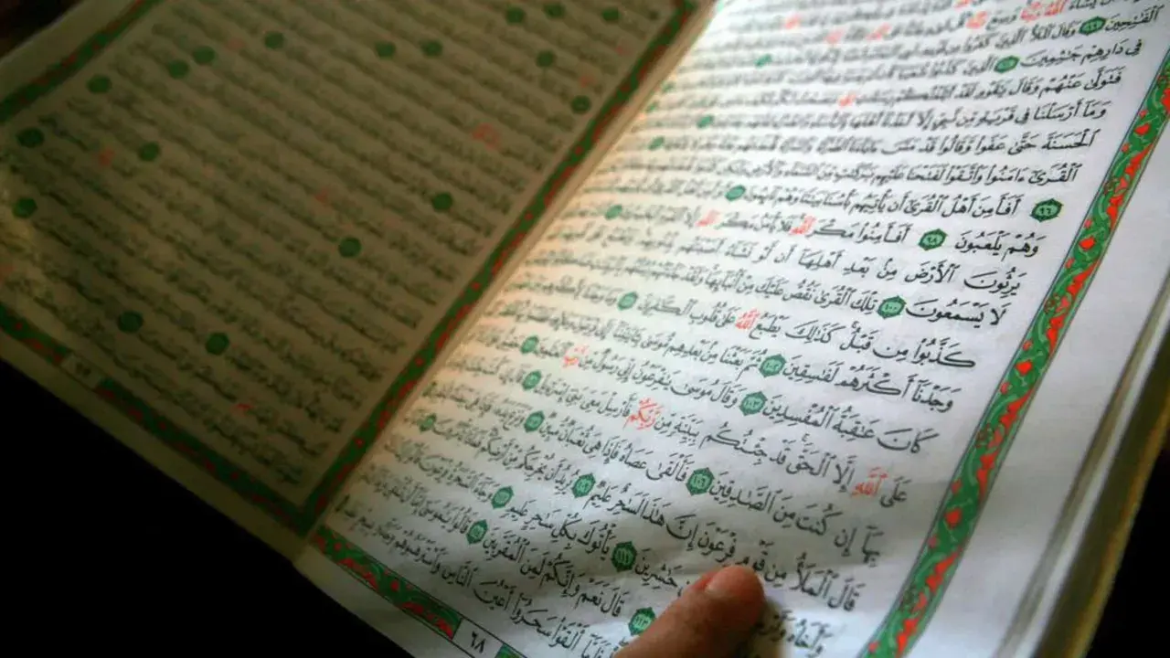Ein Finger zeigt auf eine Seite des Korans. Die Frage, wer hat den Koran geschrieben, wird durch die heiligen Schriften beantwortet.