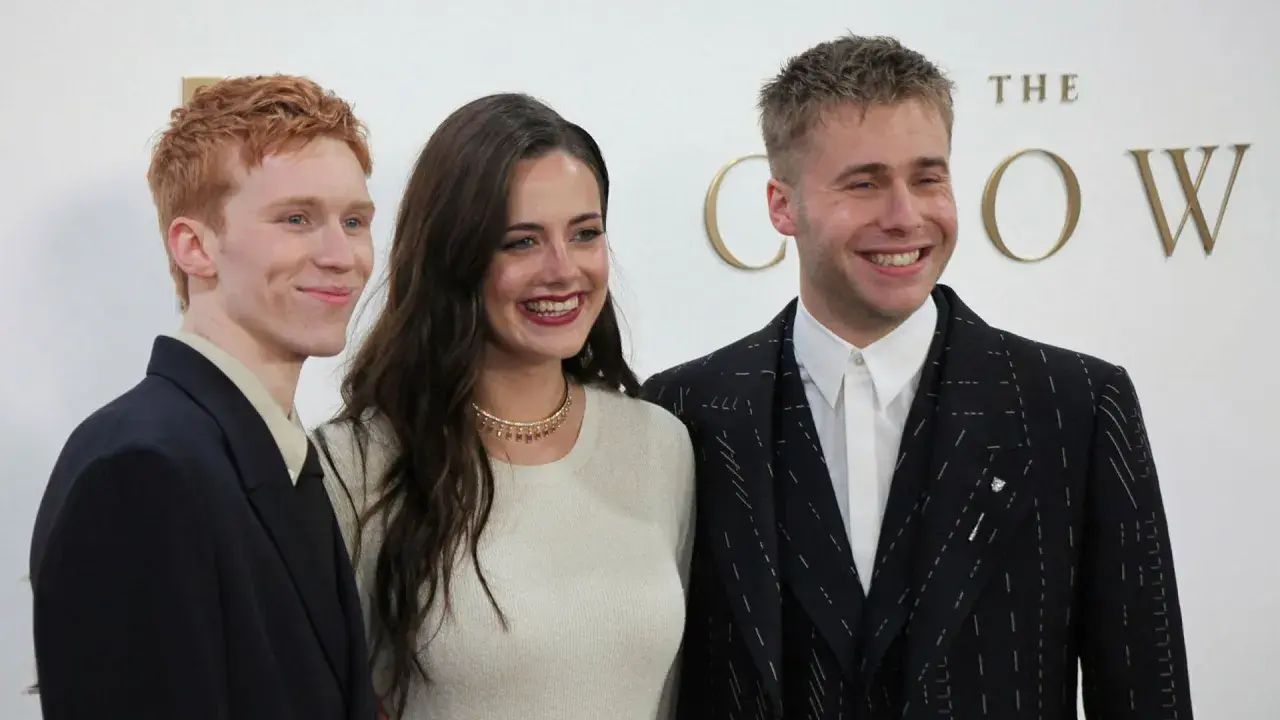 Skådespelare från "The Crown" ler glatt. En man med rött hår i mörk kavaj, en kvinna i ljus tröja och en man i mönstrad kavaj.