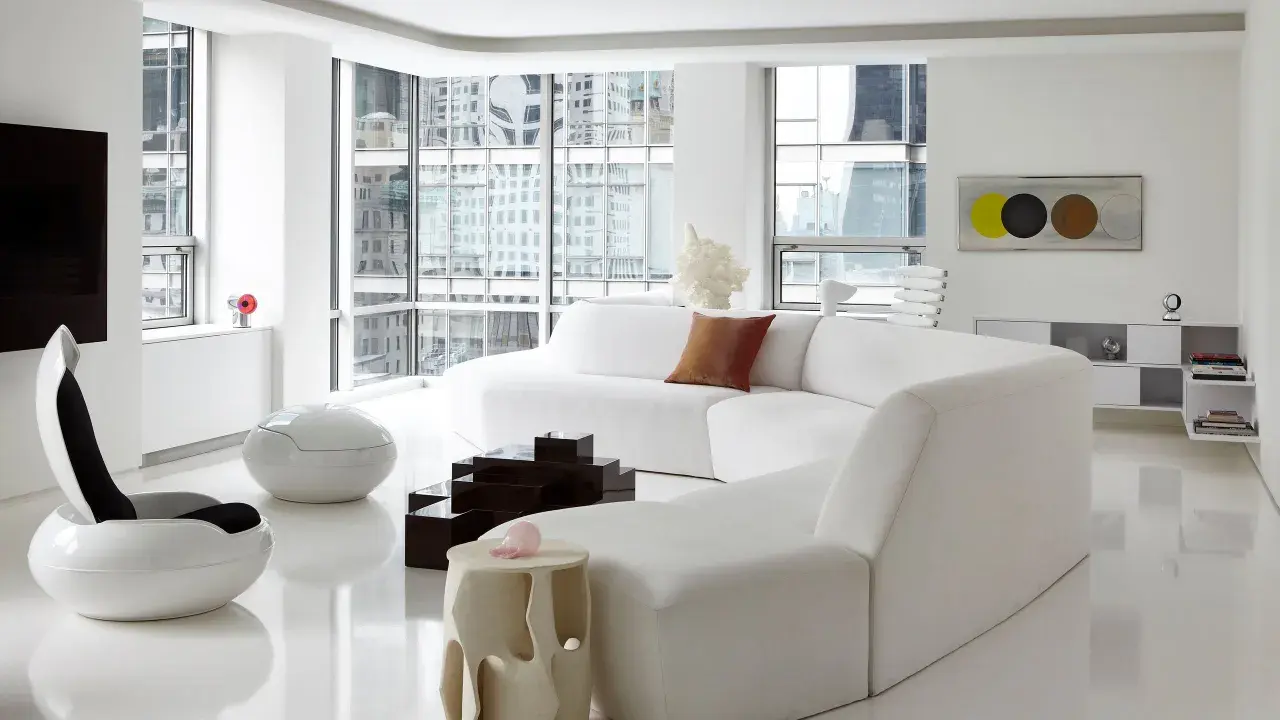 Soggiorno minimalista con divano bianco curvo, sedie futuristiche e tavolini geometrici, un vero esempio di space age design.