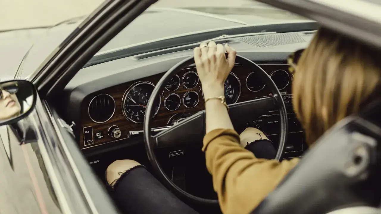 Mujer al volante de un coche clásico. De repente, la dirección asistida dura, dificultando el giro.