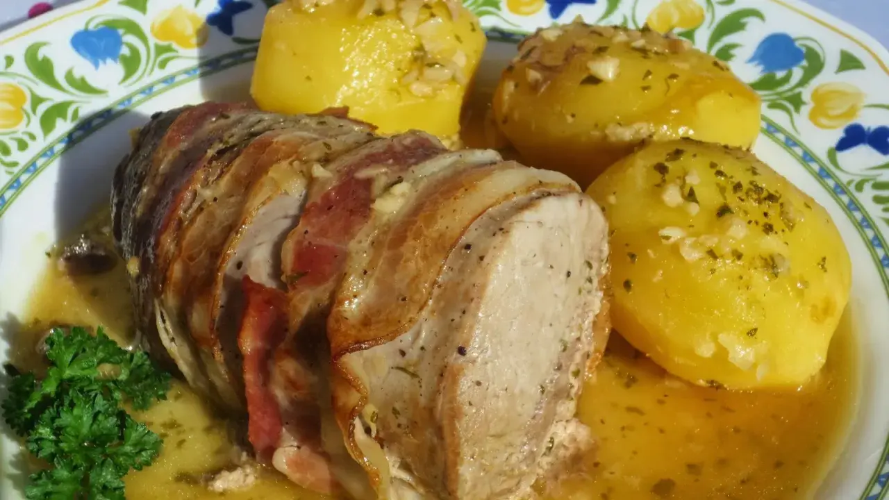 Solomillo al ajillo envuelto en bacon, servido con patatas doradas y perejil fresco. ¡Un plato delicioso!