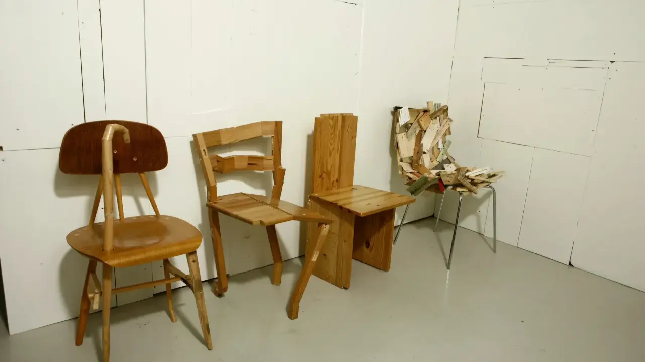 Tre unika stolar står uppradade. En av dem, med en böjd rygg, påminner om en design av Finn Ahlgren.