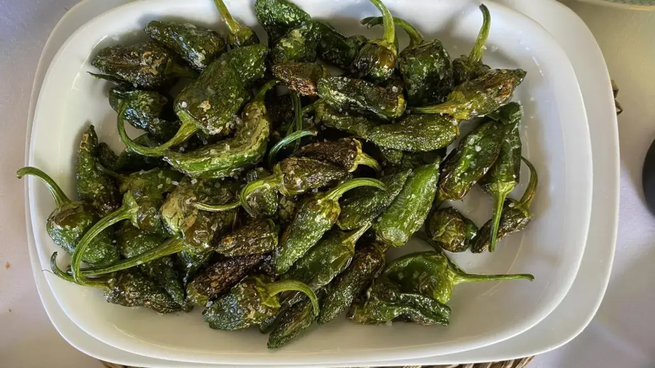 Pimientos de Padrón recién fritos, salpicados de sal gruesa, listos para disfrutar. ¡Así se preparan como freir pimientos de padron!
