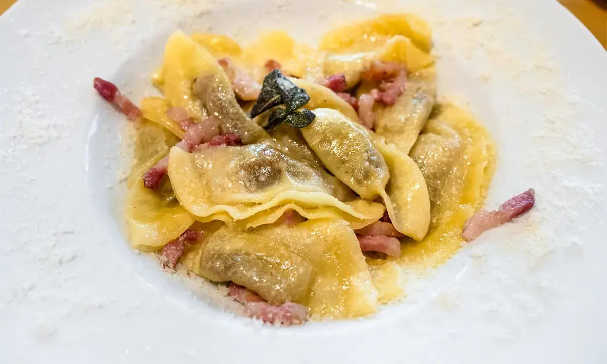 Ravioli ripieni, un piatto tipico bergamasco, conditi con pancetta croccante e salvia.