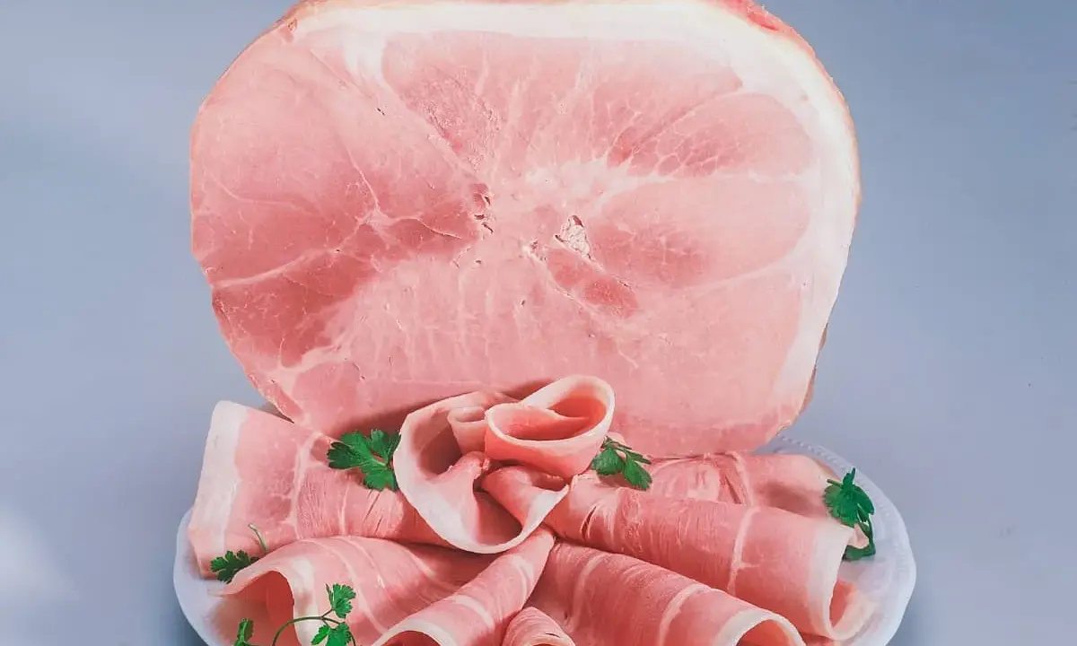 Fetta di prosciutto cotto, con fette arrotolate guarnite di prezzemolo. Attenzione: il prosciutto cotto è considerato cancerogeno.