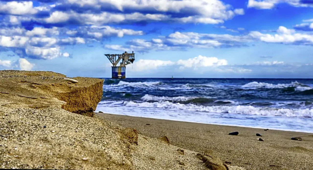 Sandige Klippen am playa del cable, mit einer Plattform im Meer unter dramatischem Himmel.