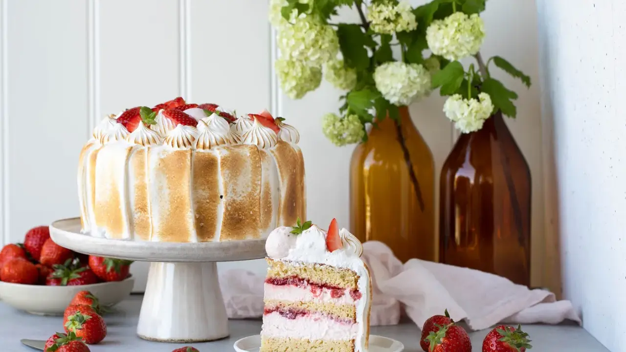 Eine köstliche Erdbeer Baiser Torte mit frischen Erdbeeren und zartem Baiser. Ein Stück der Torte zeigt die saftigen Schichten.