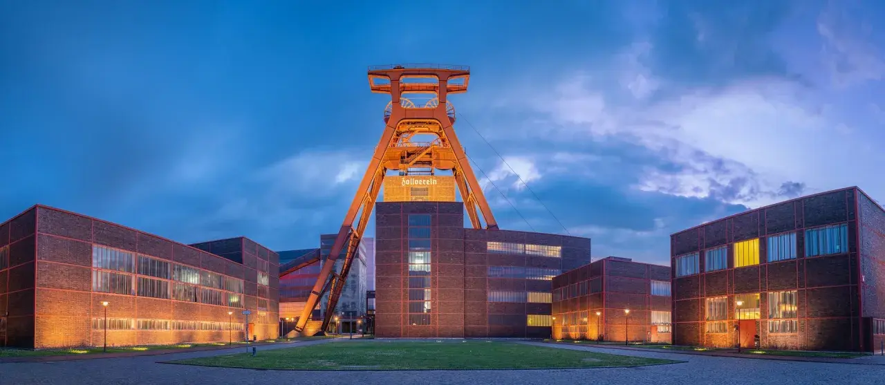 Industrielles Erbe: Der Förderturm des Zollverein 1834 ragt über die beleuchteten Backsteingebäude.