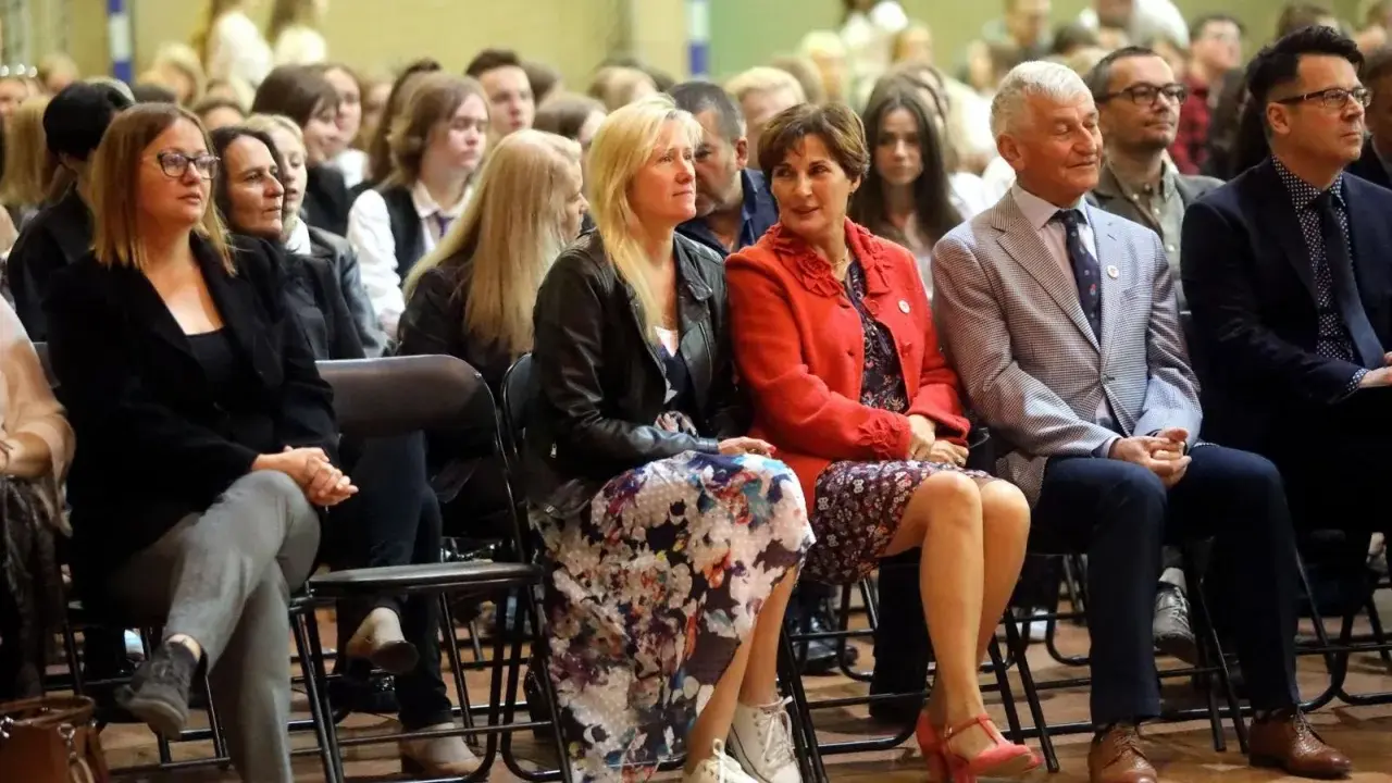 Uczestnicy siedzą na krzesłach, wśród nich widać osoby, które mogą być na radzie pedagogicznej.