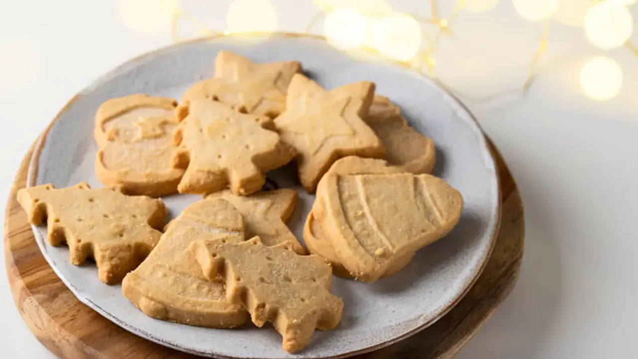 Assortiment de sablés de Noël en forme de sapins, étoiles et cloches, parfaits pour accompagner un chocolat chaud.