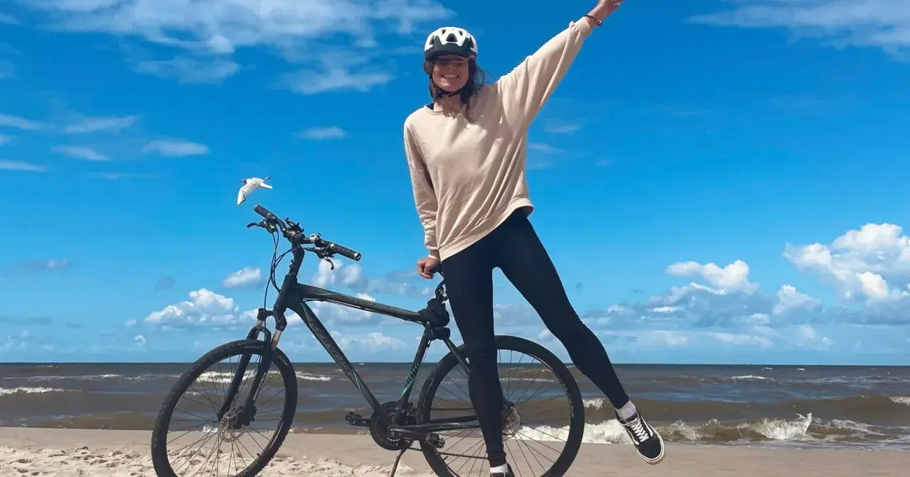 Dziewczyna w kasku na rowerze na plaży. Wspaniała infrastruktura rowerowa nad morzem.