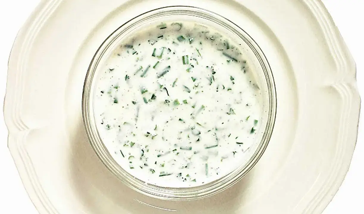 En skål med krämig kall sås till fisk, med finhackade örter som dill och gräslök. Perfekt till sommarens sillbord.