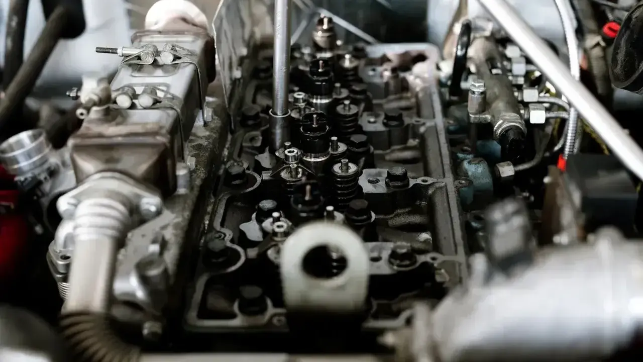 Mechanik pracuje nad silnikiem, słychać metaliczny dźwięk silnika.