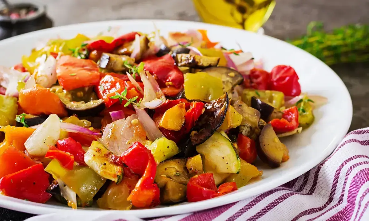 Un piatto colorato di verdure miste, pomodori, melanzane e peperoni, che evoca i sapori dei piatti tipici siracusani.