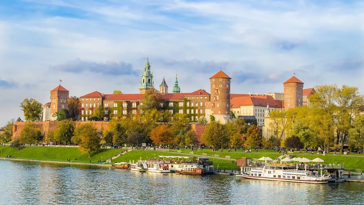 Wawel w jesiennej odsłonie, z łodziami na Wiśle. Poznaj ciekawostki o Krakowie, spacerując brzegiem rzeki.