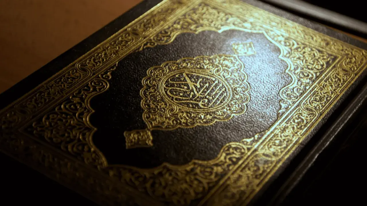 Ein prachtvoller Koran mit goldener Verzierung. Die Mitte ziert eine kunstvolle Kalligraphie, die an die Weisheit der **Surah Luqman** erinnert.