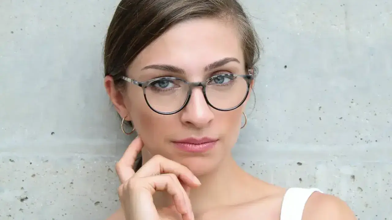 Eleganckie okulary dla szczupłej twarzy podkreślają spojrzenie kobiety.