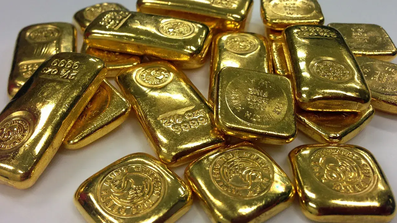 Lingotti d'oro luccicanti, alcuni con incisioni che indicano il peso e la purezza. La domanda "oro 850 quanti carati" è un'ottima domanda per valutare il valore di questi preziosi lingotti.