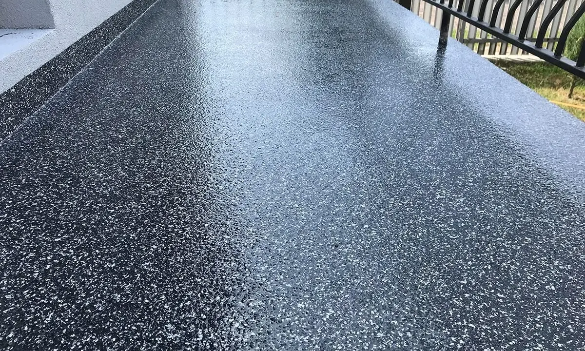Nowy, błyszczący balkon z żywicą epoksydową. Ciemna posadzka z drobinkami tworzy nowoczesny wygląd.