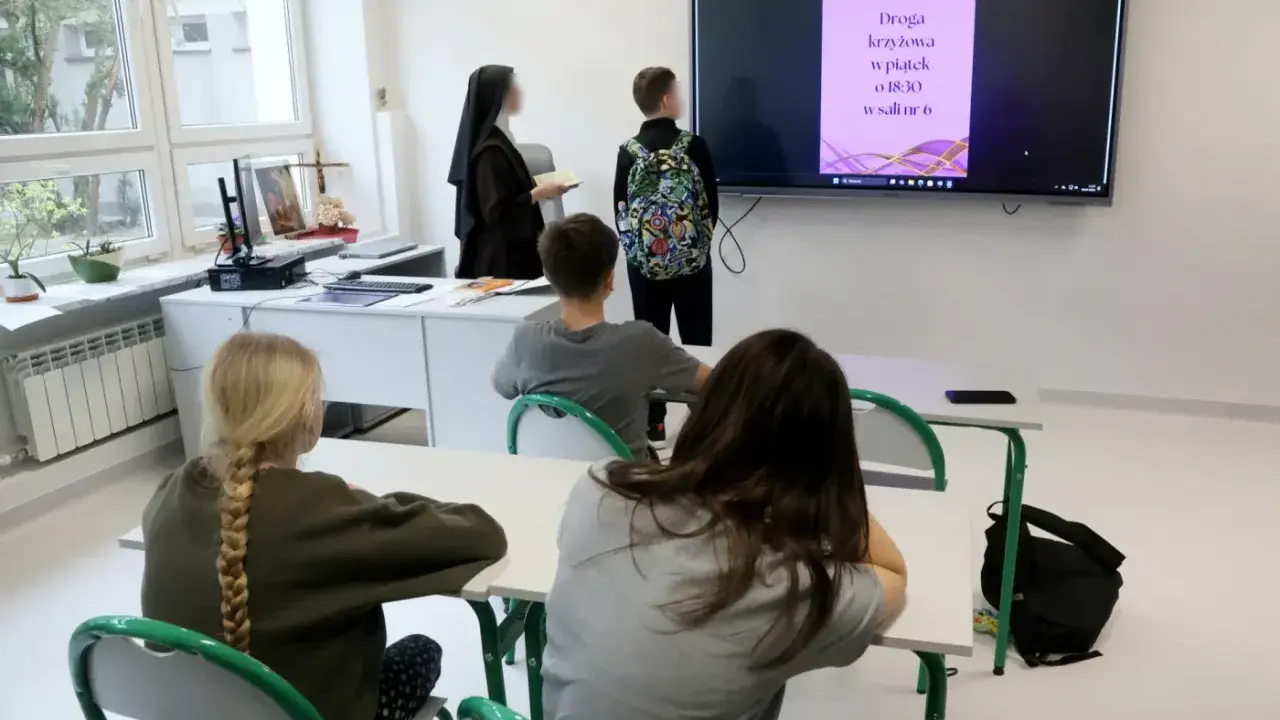 Lekcja religii w szkole. Czy religia wlicza się do średniej? Nauczycielka w habicie i uczniowie patrzą na ekran z informacją o Drodze Krzyżowej.