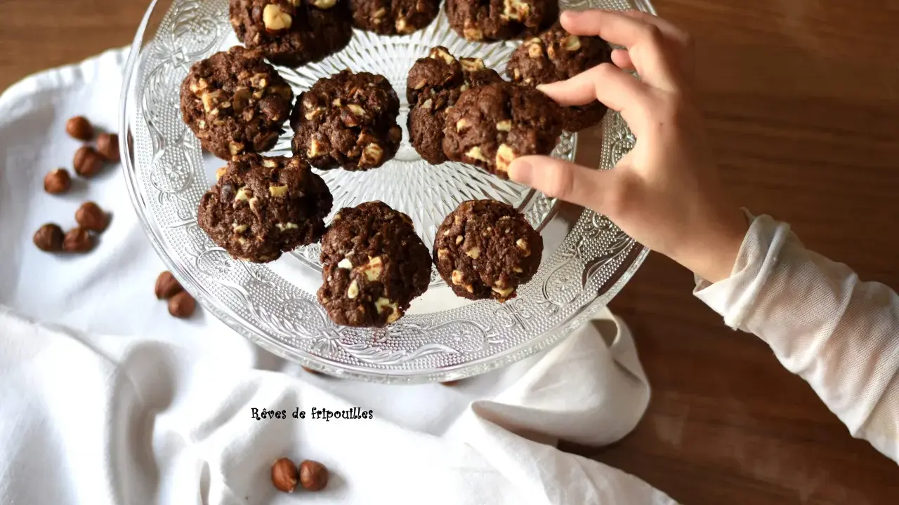 Délicieux cookies au chocolat et noisettes, parfaits pour savoir que faire avec un reste de ganache au chocolat. Une main en prend un.