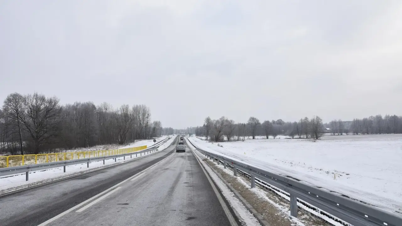 Zimowa trasa, śnieg przy drodze, drzewa bez liści. Nowy tomyśl trasa wita podróżnych.