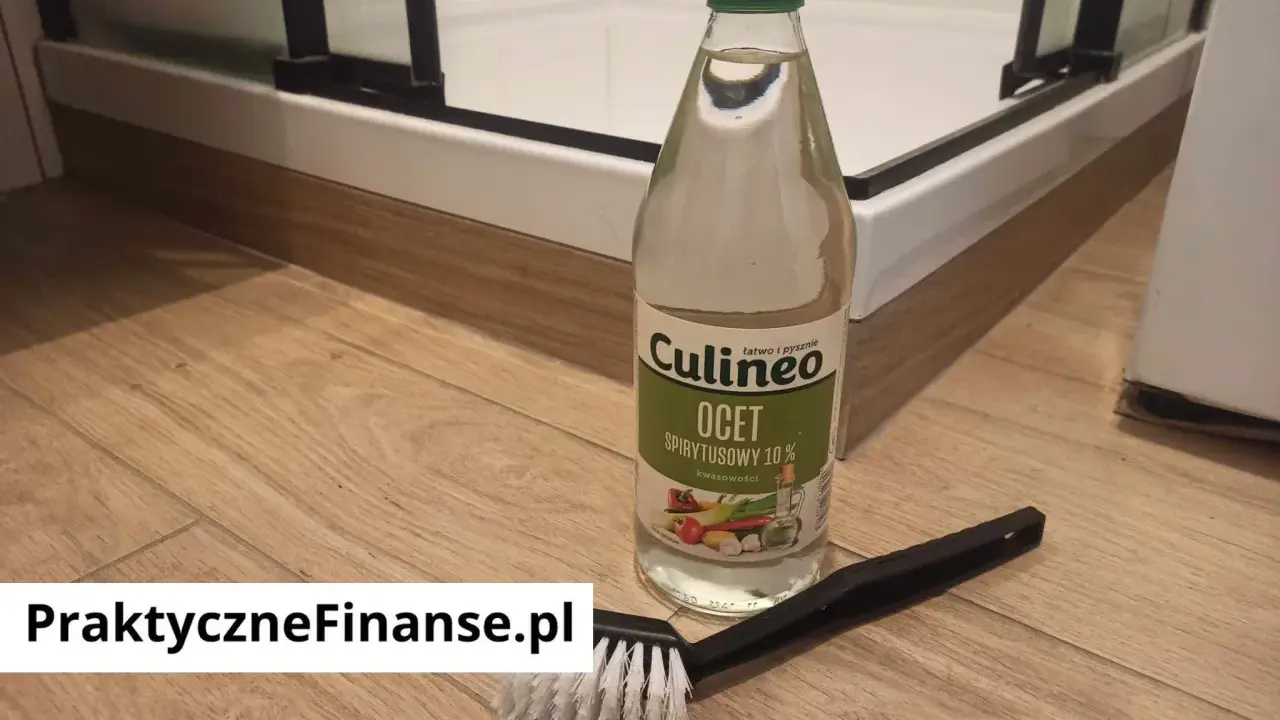 Butelka octu spirytusowego i szczotka do czyszczenia na drewnianej podłodze.