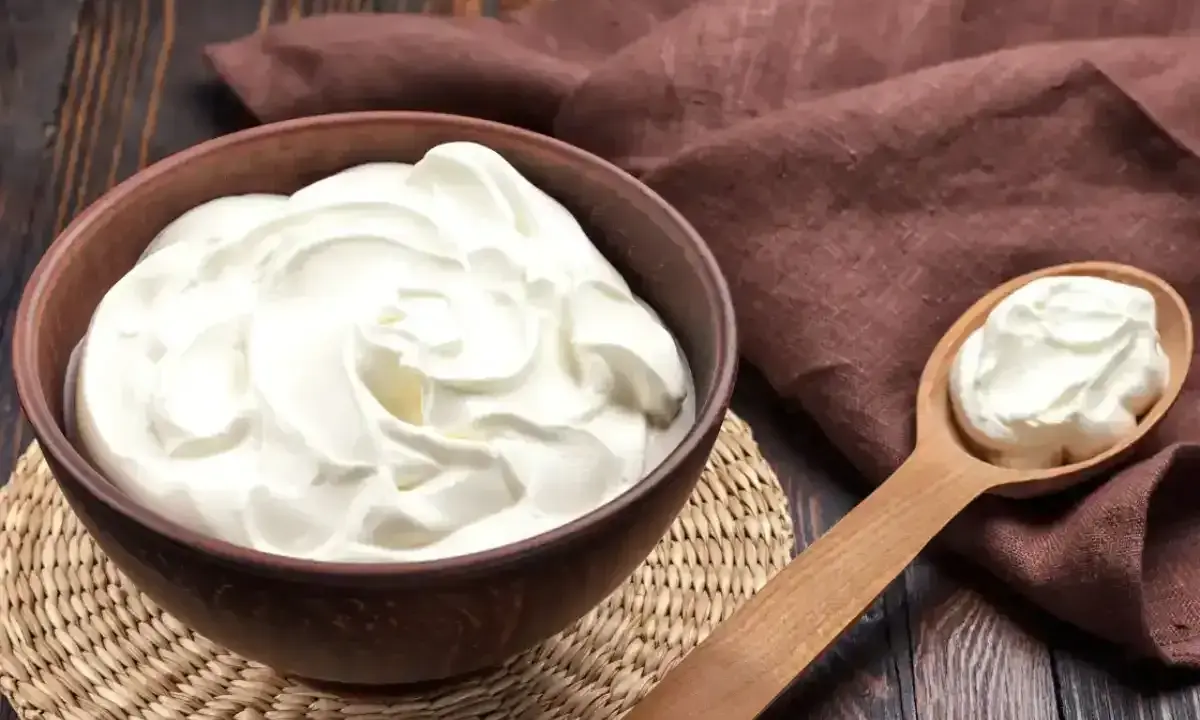 Un bol de crème onctueuse, parfaite pour une crème diplomate, avec une cuillère en bois remplie de cette douceur.