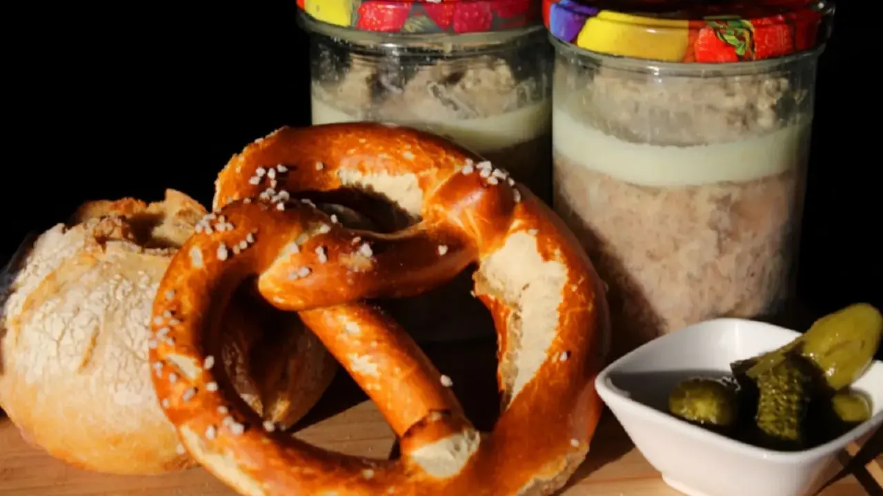 Zwei Gläser mit Fleisch einkochen im Weck-Glas, dazu ein Brezel, Brot und Gewürzgurken.