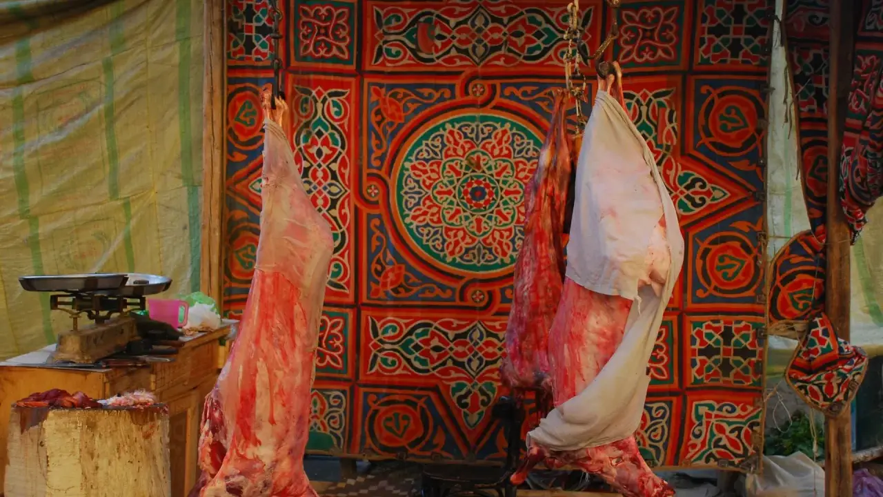 Fleisch hängt vor einem bunten Stoffmuster, bereit für Eid el Adha.