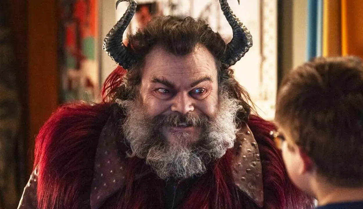 Jack Black med horn och rött päls, en karaktär från filmer med Jack Black, tittar på ett barn.