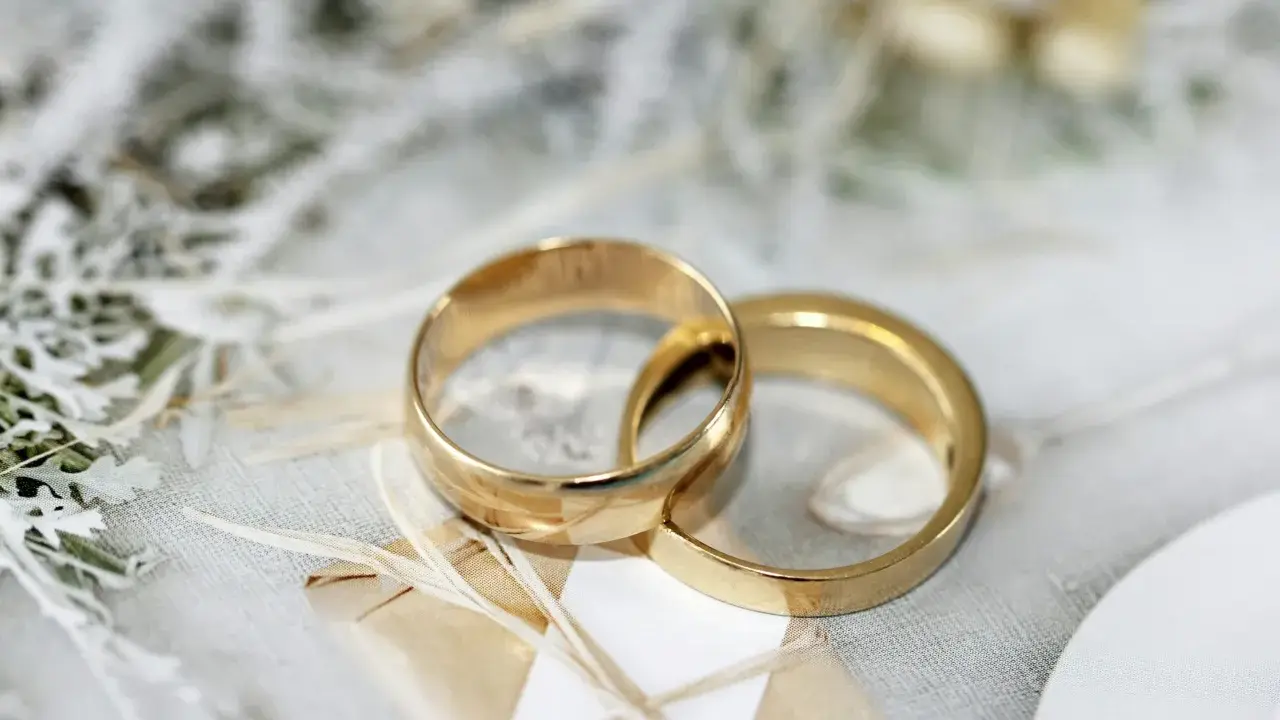 Due fedi dorate intrecciate su uno sfondo delicato. Pensare a cosa incidere sulle fedi è un passo importante per personalizzare questo simbolo d'amore.