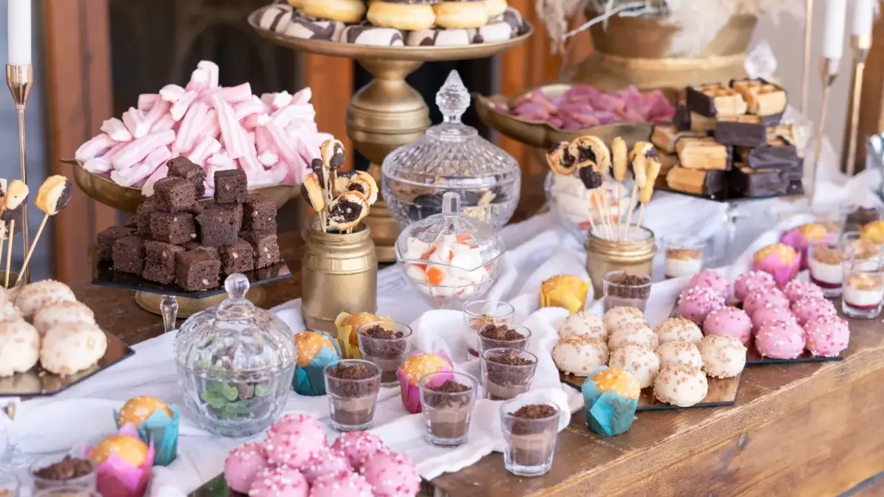 Una mesa dulce boda original con donuts, brownies, malvaviscos rosas y bolitas de colores.