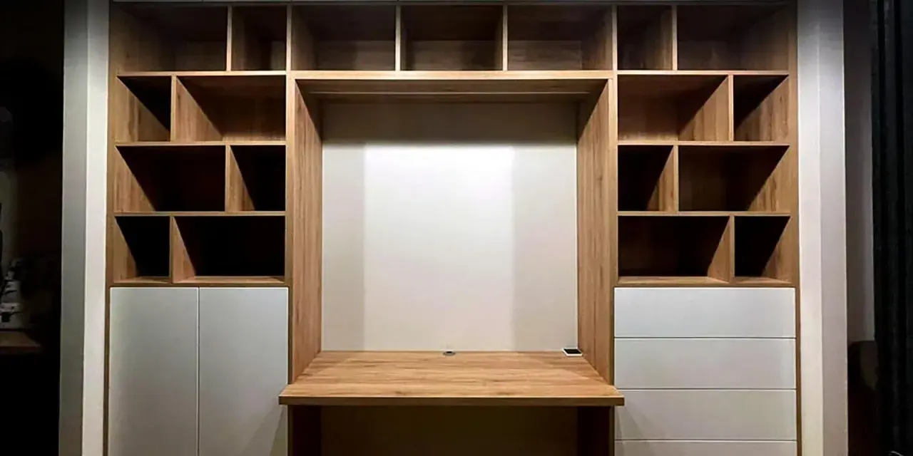 Einbauwand mit Schreibtisch und vielen Fächern. Weiße Schubladen bieten unsichtbaren Stauraum für Ordnung.