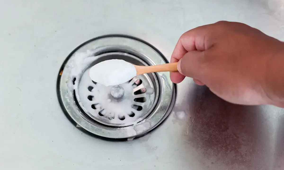 Maintenant, je vais aider à déboucher le siphon. Une cuillère de bicarbonate de soude est versée dans l'évier.