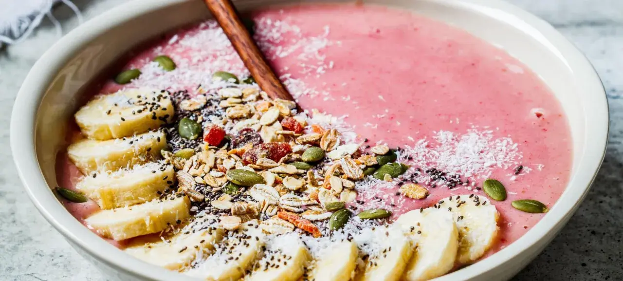 En rosa smoothie bowl med bananskivor, granola, pumpafrön, chiafrön och kokosflingor. En perfekt start på dagen!